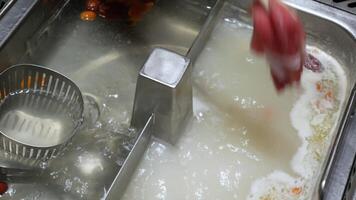 4k video POV to the hotpot shabu shabu in chinese Sichuan style while using chopstick pick pork meat sliced put into pot with vetgetable.