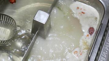 4k video POV to the hotpot shabu shabu in chinese Sichuan style while using chopstick pick pork meat slicedfrom hot pot to eat.