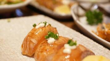 fechar acima seletivo foco para uma prato do japonês Comida com Sushi enquanto mão usando pauzinho para escolher acima uma Sushi a partir de uma prato dentro almoço tempo. video