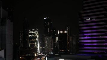 aerial night time landscape skyline of Bangkok city in night time with light on many highrise skyscraper buildings with some traffic. video