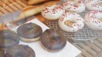 Schwenken Aussicht zu das Stall von frisch Donuts im Geschäft durch Brille Fenster im Gebäck Geschäft. video