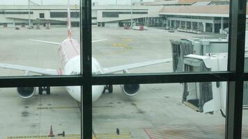 avião chegado para aeroporto terminal e terra tratamento serviço é trabalhando enquanto chegada voar do ar Ásia A320 avião às Aerobridge video