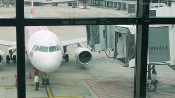 suelo manejo servicios de llegada avión aeronave mientras estacionamiento a el portón a llegada terminal internacional aeropuerto en verano fiesta tiempo de día. video