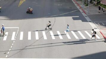 aéreo ver a el calle a el cruce intersección mientras concurrido personas cruce el calle en el ciudad centrar verano tiempo de día. prisa hora calle ver peatonal caminando video