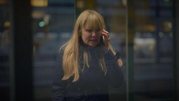 loiro mulher falando Bravo em Móvel telefone às estação de trem discutindo video