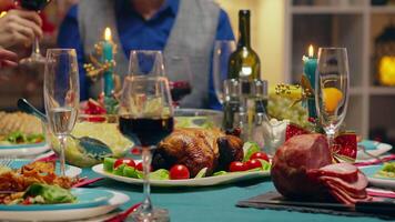 vicino su di padre affettare il pollo per il suo famiglia a Natale riunione. tradizionale festivo Natale cena nel multigenerazionale famiglia. godendo natale pasto festa nel decorato camera. grande famiglia riunione video