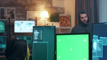 fêmea cyber terrorista vestindo uma moletom com capuz trabalhando em computador com verde tela. video