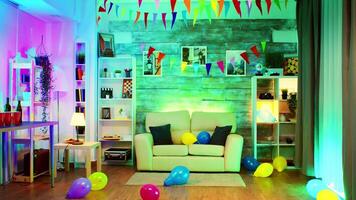 Party decorated room with neon lights on the wall and a disco ball, drinks, balloon and chips. video