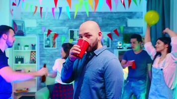 Zoomen im Schuss von jung Mann Trinken Alkohol während Party machen mit seine freunde beim Hochschule Party mit Neon- Beleuchtung video