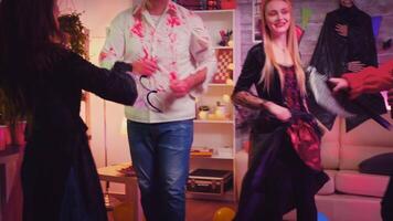 Group of young people disguise in spooky characters at halloween party having fun and dancing in decorated room video