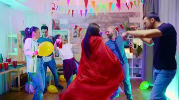 Zoom in shot of girl dressed up like a superhero with red cape at wild party with neon lights. video