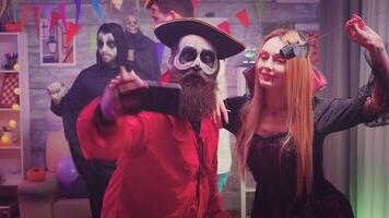 assustador pirata e sangrento bruxa personagens levando uma selfie às dia das Bruxas festa enquanto seus amigos estão dançando e tendo Diversão dentro decorado casa video