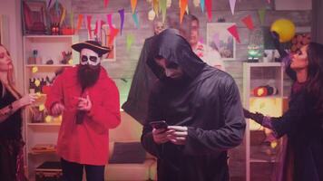 Bored young man dressed up like grim reaper at halloween party. video