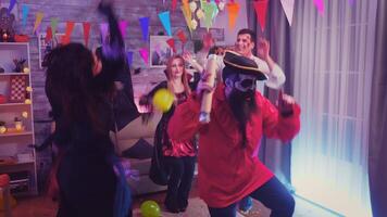 barbado pirata con papel picado teniendo divertido a Víspera de Todos los Santos celebracion mientras amigos son bailando en el antecedentes en decorado habitación video