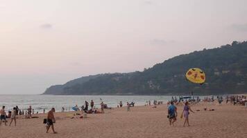 viele Menschen entspannend auf Strand Aufpassen Sonnenuntergang Sonnenuntergang beim Karon Strand mit schön Sonnenuntergang golden Vanille Himmel, Phuket tropisch Insel Ferien Urlaub im 4k Video