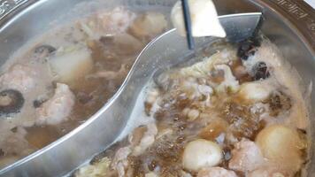 cerca arriba de personas comiendo juntos utilizando palillos poniendo vegetal y carne dentro el estofado rojo picante hirviendo chino Sichuan estilo sopa video