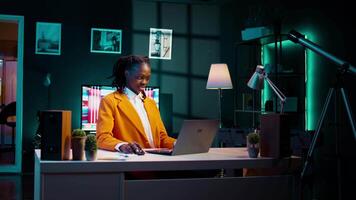 African american student working on her bachelor paper essay at home, writing ideas from online research. Girl exploring digital libraries and academic databases for additional resources. Camera B. video