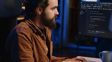 concentré programmeur en buvant café dans appartement tandis que résolution base de données les erreurs sur ordinateur. à distance travail il administrateur concentré sur finalisation codage projet dans Accueil bureau, caméra une video