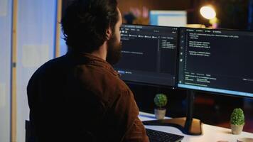 Computer scientist at home office desk writes binary code scripts and drinks from mug of coffee. IT expert in apartment enjoying tea while using programming to safeguard consumer data, camera A video