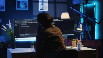 Man doing IT support job from apartment personal office drinking cup of coffee while coding. Software developer enjoying hot beverage and writing lines of code on computer, camera A video