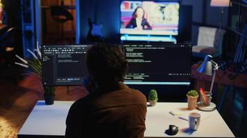 Man doing IT support job from apartment personal office drinking cup of coffee while coding. Software developer enjoying hot beverage and writing lines of code on computer, camera B video