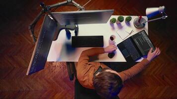 Top down view of software programmer finishing remote job shift, packing backpack, leaving office after finishing project. Aerial shot of IT admin putting laptop in bag, sitting up from desk chair video