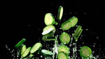 Pieces of fresh cucumbers with drops of water fly up and fall. On a black background.Filmed is slow motion 1000 fps. video