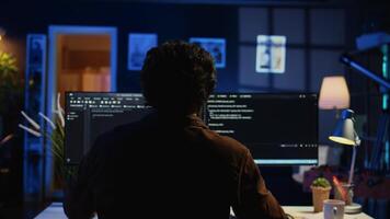 Engineer wearing headphones while using coding to fortify security, remotely working for IT company. Software expert listening music and upgrading binary code scripts on computer, camera B video