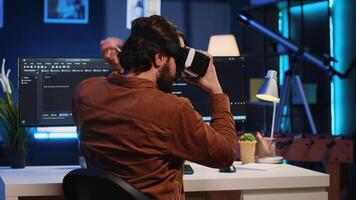 Remote software developer using VR goggles in personal office at home to do javascript programming. IT engineer wearing virtual reality headset in order to visualize lines of code, camera A video