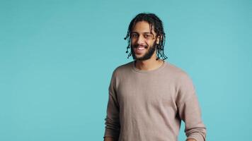 Man doing thumbs up hand gesturing, showing approval, having positive mood. Cheerful BIPOC person presenting confirmation, doing agreement finger sign, studio background, camera B video