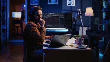 Engineer typing code in apartment office, using javascript programming language to develop software application. It admin using multimonitor desktop setup and notebook to finish tasks, camera B video