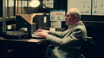 Senior inspector gathering all case files in a folder to study for new clues, uses forensic techniques to examine evidence in archive. Wheelchair user working on uncovering information. Camera A. video