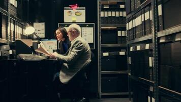 Private agents reading classified records to uncover new case clues, team strategizes next steps working in archive room. Detectives brainstorm strategies based on insights from old files. Camera B. video