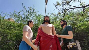 Jezus standbeeld - kleren strippen - achteruit schot video