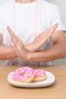 woman hand reject donut dessert, female refuse Unhealthy junk food. Dieting control, Weight loss, Obesity, eating lifestyle and nutrition concepts photo