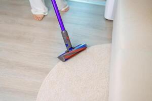 Woman cleaning Carpet with cordless Vacuum cleaner. Housewife using wireless Hoover for big cleaning home. Housework, Housecleaning, Housekeeping, Removes dust, Domestic hygiene and daily routine photo