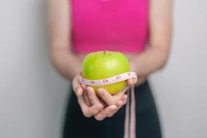mujer mano sostener verde manzana, contento hembra aptitud escoger Fruta es sano alimento. dieta control, peso pérdida, obesidad, comiendo estilo de vida y nutrición conceptos foto