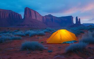 ai generado iluminado tienda en Desierto crepúsculo en contra fondo de majestuoso rock formaciones foto