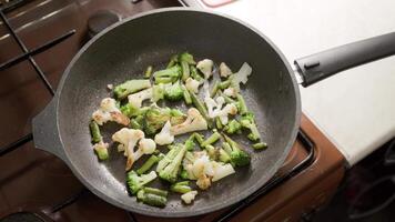 female hands adds a scrambled eggs to fried vegetables while cooking omelette video