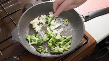 caucásico mujer emocionante fritura vegetales en hirviendo petróleo con tenedor video