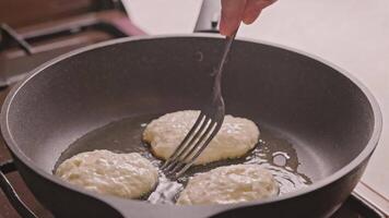 hands with two forks flipping semi-liquid dough roasting on cast iron pan covered with vegetable oil video