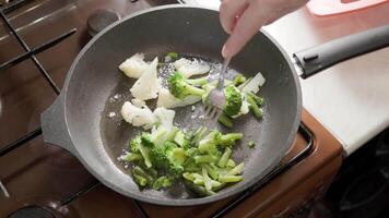 caucasico donna eccitante frittura verdure nel bollente olio con forchetta video