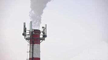 Thermal power station pipe outgoing smoke, steam and isicles on telecom antennas video