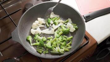 caucasian woman stirring frying vegetables in boiling oil with fork video