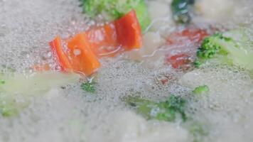 schuim verschijnen in koken bloemkool, broccoli en rood klok peper - detailopname video