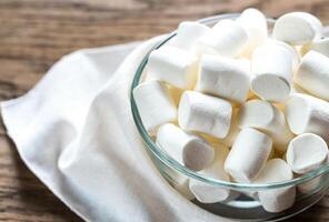 Bowl of marshmallows on the wooden background photo