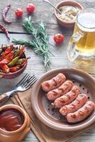 Grilled sausages with appetizers and mug of beer photo