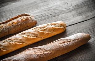 Three baguettes on the wooden background photo