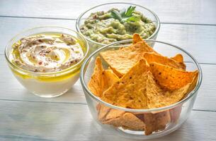 Bowls of hummus and guacamole with tortilla chips photo