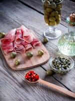 Jamon with capers and olives on the wooden board photo